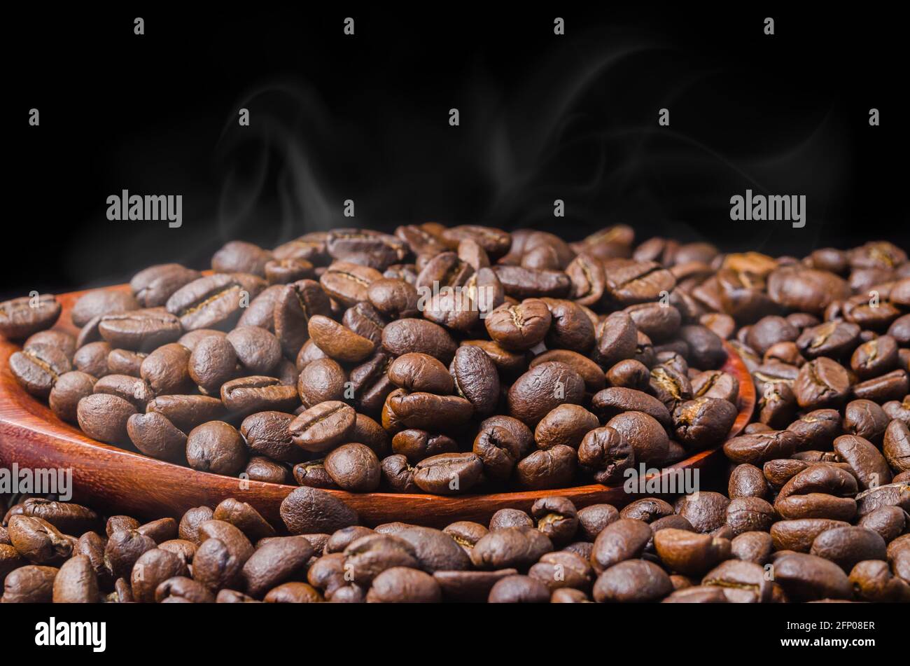 Coffee beans fresh roast with smoke on black background Stock Photo - Alamy