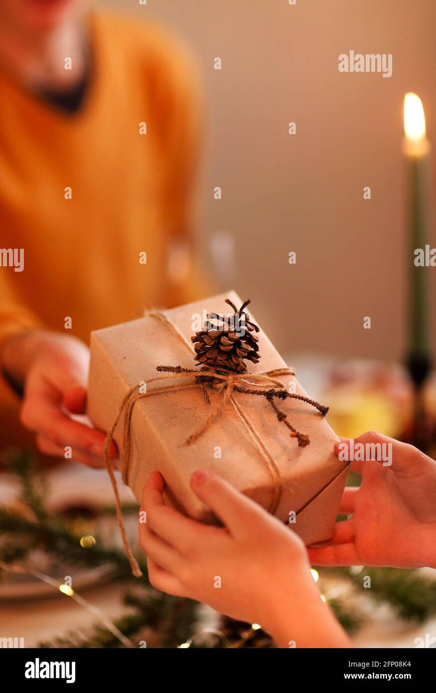 Soft focus of unrecognizable person giving wrapped gift to friend while sitting at table and celebrating Christmas together Stock Photo