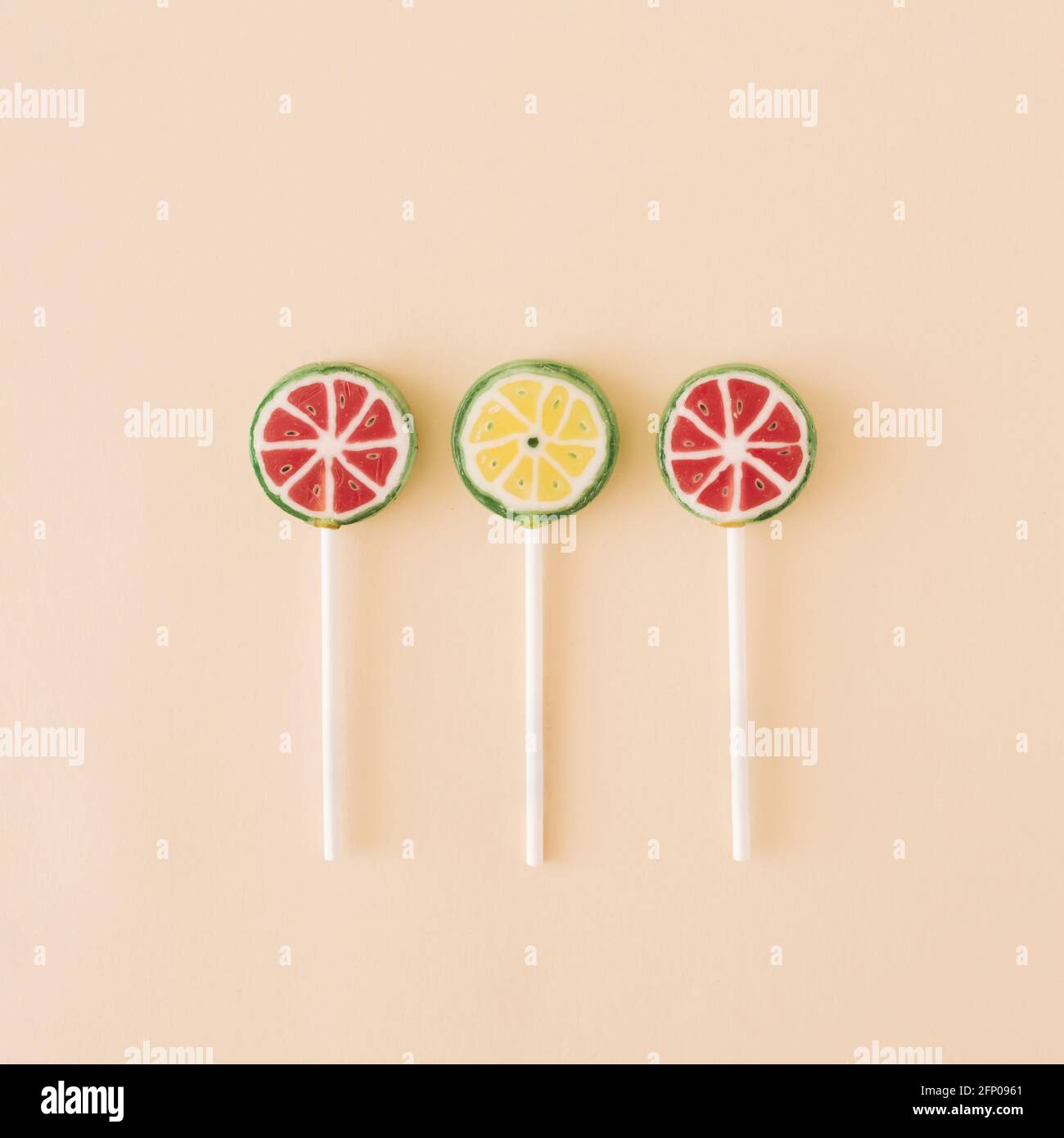 Three fruit lollipops that face on watermelons and limes on a cream