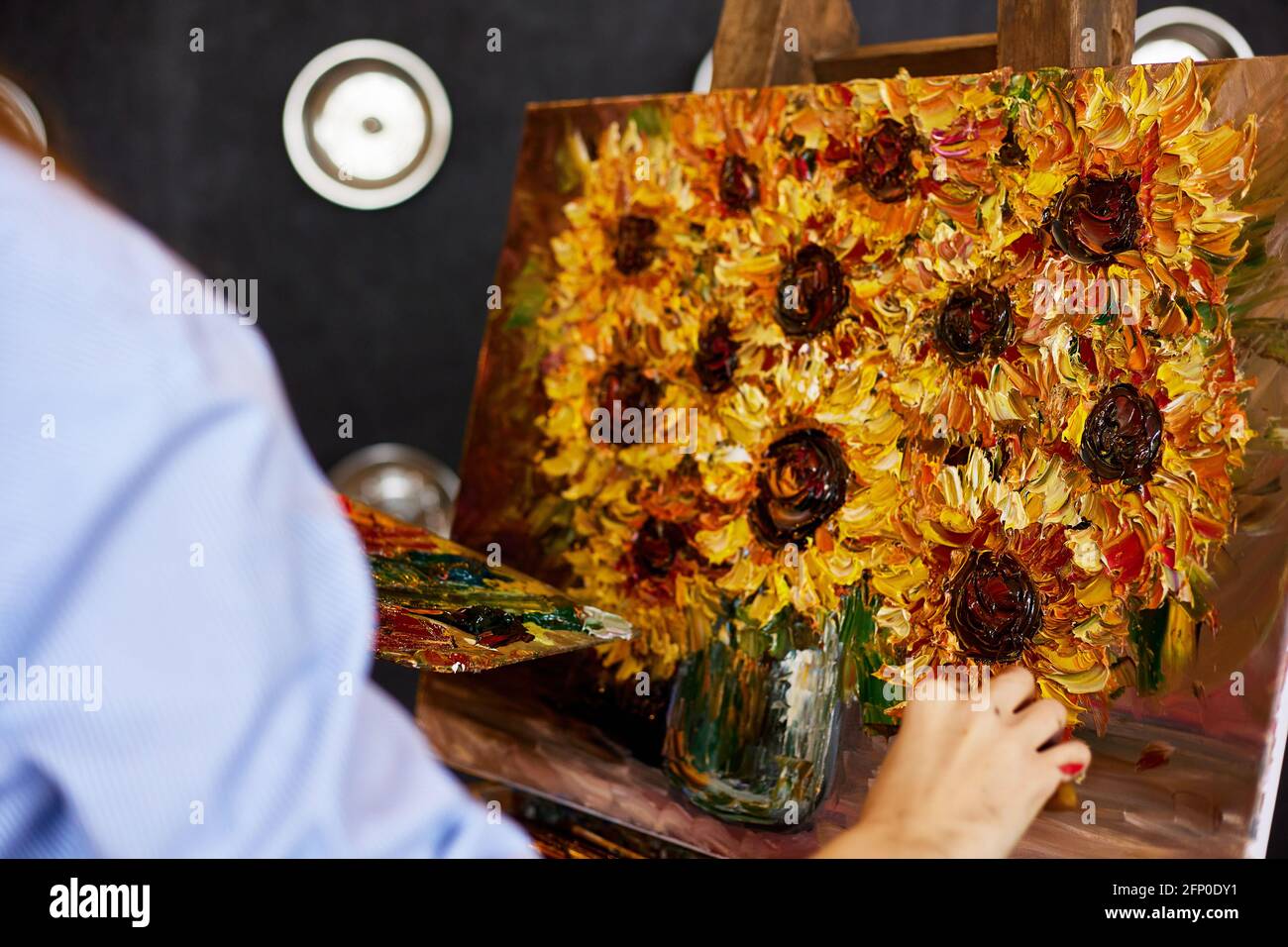 Young beautiful female artist painting still life with sunflower on ...