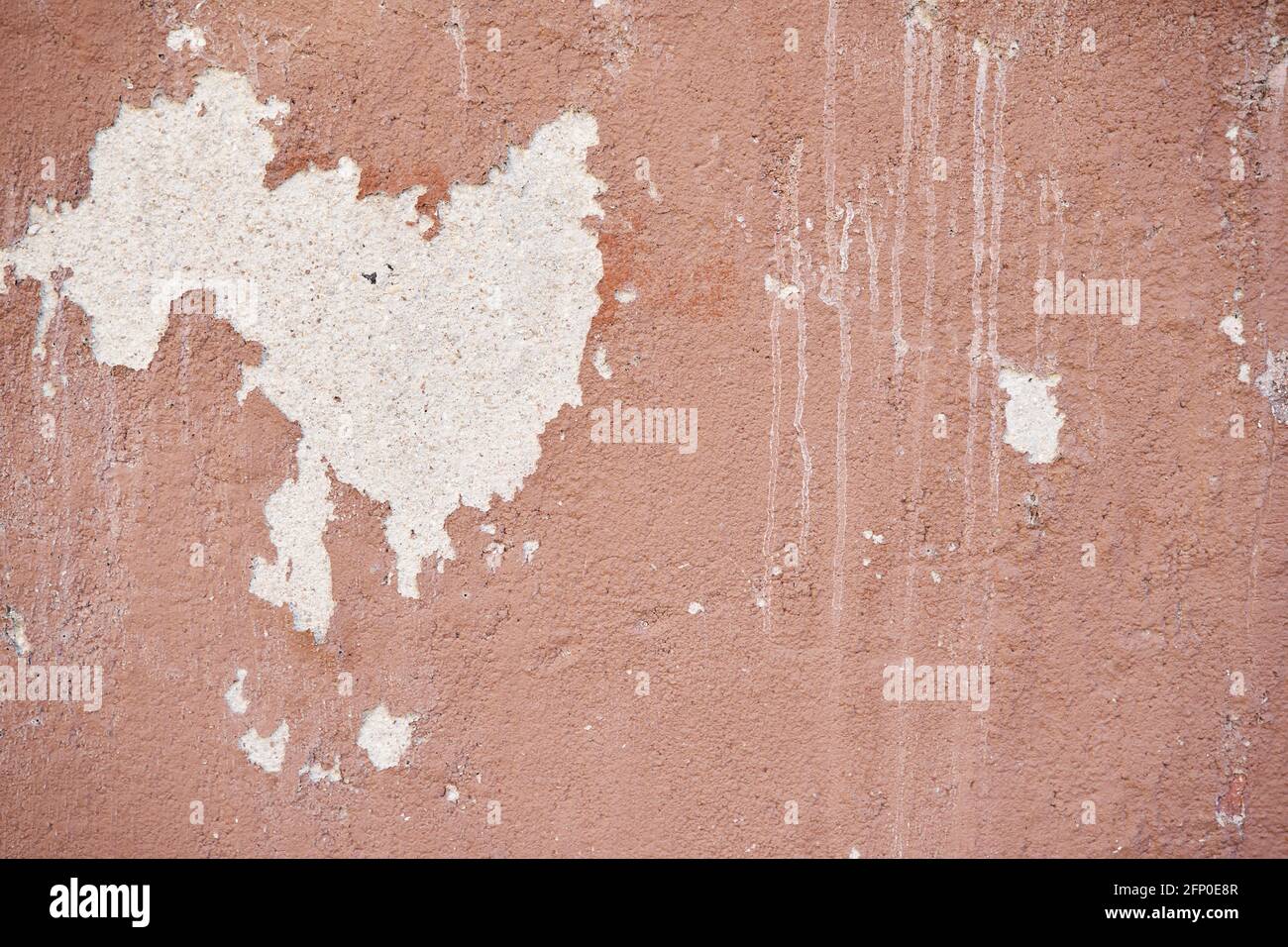 Horizontal photograph of the Abstract texture of terracotta painted stucco wall with peeling paint. Stock Photo