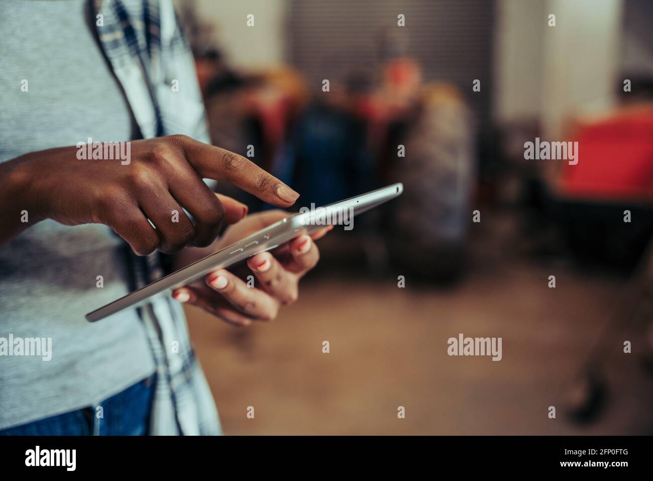 Close up mixed race female typing on digital tablet standing in farm store room  Stock Photo