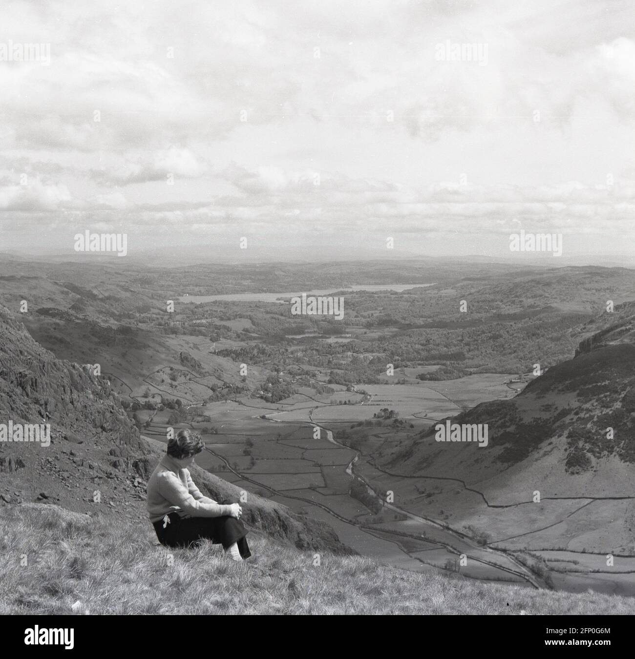 1961, historical picture, its summer time and a lady walker is sitting on a grassy hillside or uplands taking in the glorious view of the valley below and surrounding landscape, Socttsh Highlands, Scotland, UK. Stock Photo