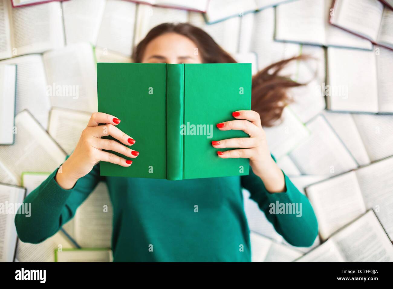 Top view of anonymous female student lying on books and reading during exam preparation Stock Photo