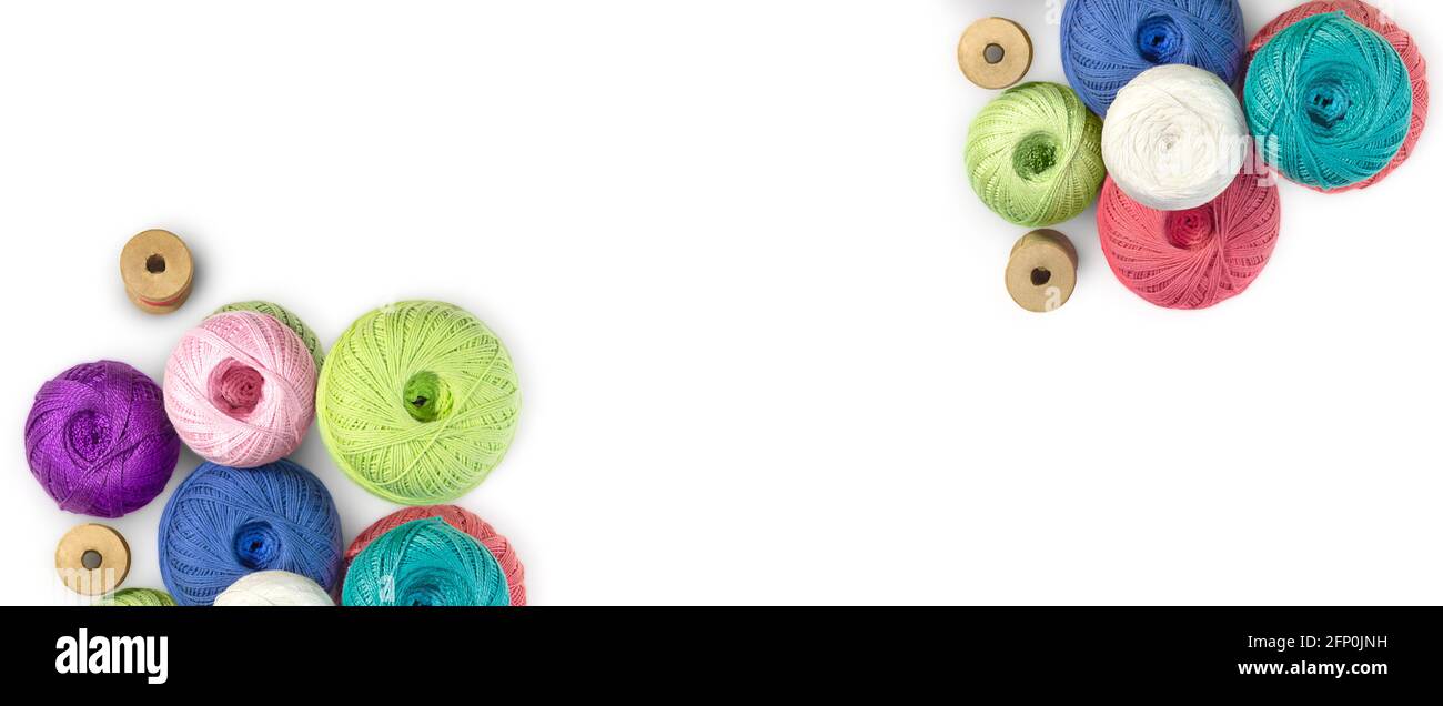 Multicolored balls and bobbins of woolen yarn, wooden thread sleeves on white isolated background. Banner for needlework, handmade. view from above. I Stock Photo