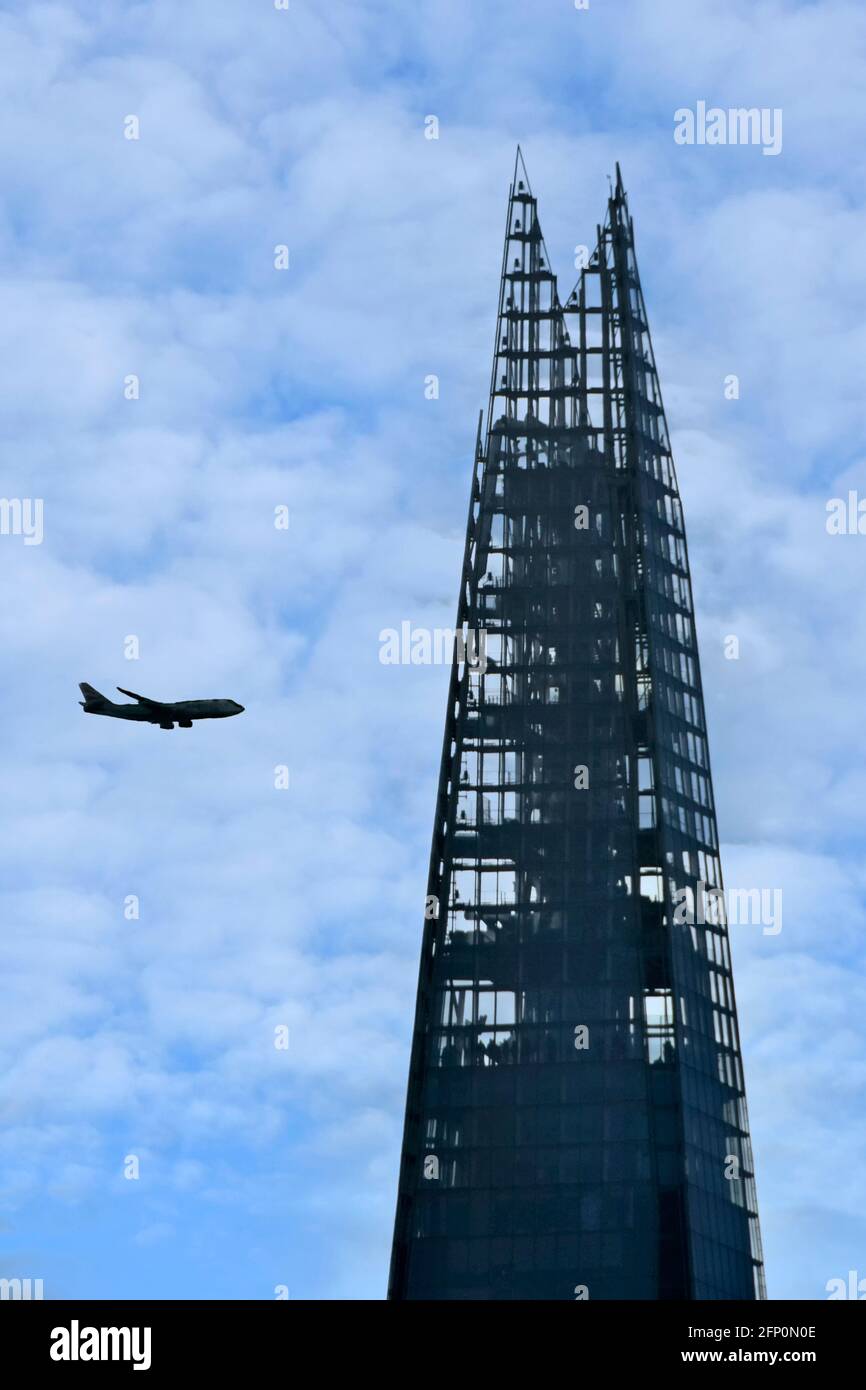 Silhouette view top London Shard landmark skyscraper building includes public viewing platform airplane beyond on flight path descent to Heathrow UK Stock Photo