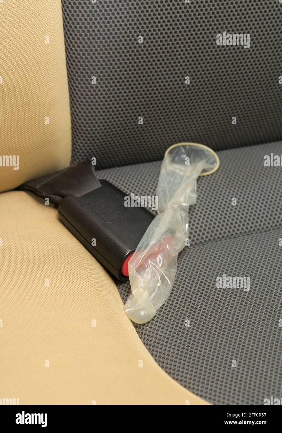 used condom over seatbelt on car back seat Stock Photo