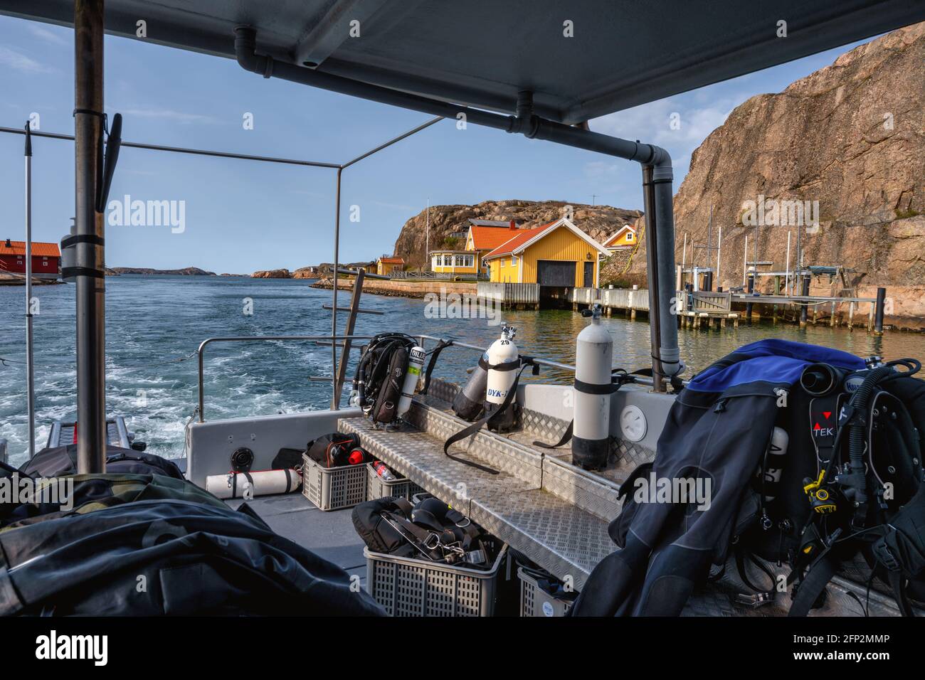 April 17, 2021 - Hamburgsund, Sweden: This picturesque fishing village on the Swedish West coast seen from the deck of a returning dive boat. Rocks and a blue sky in the background Stock Photo