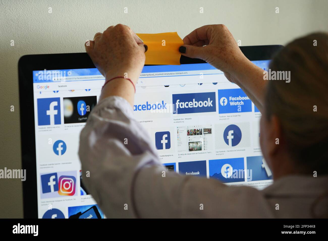 In this photo illustration an internet user covers the camera of her  computer as screen displays logos of the social networking of the Facebook  on May 20, 2021 in Amsterdam,Netherlands. Dutch municipalities