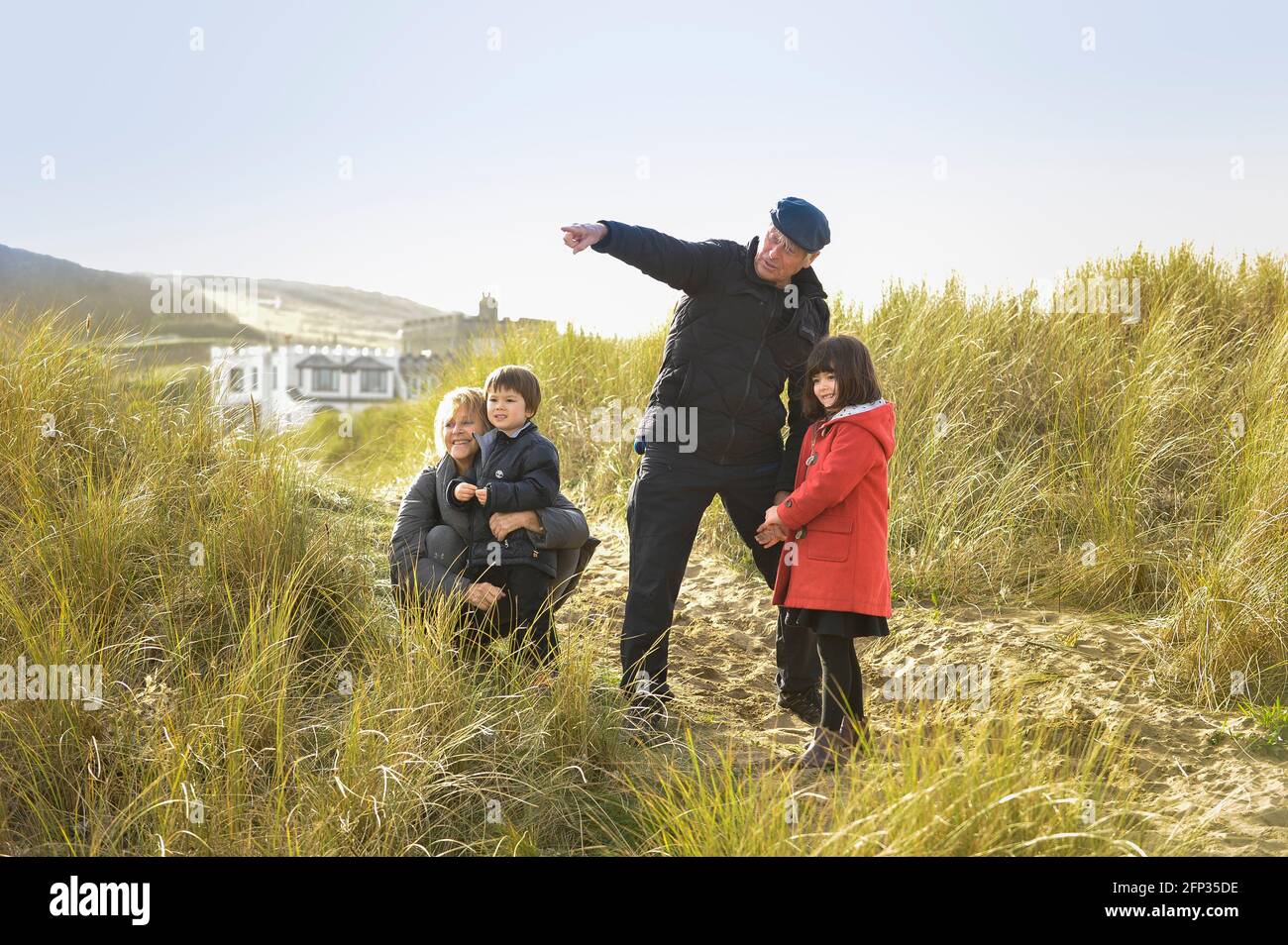 A retired couple spending time with their grandchildren on a holiday in Cornwall UK. Walking through sand dunes and playing on the beach. Stock Photo