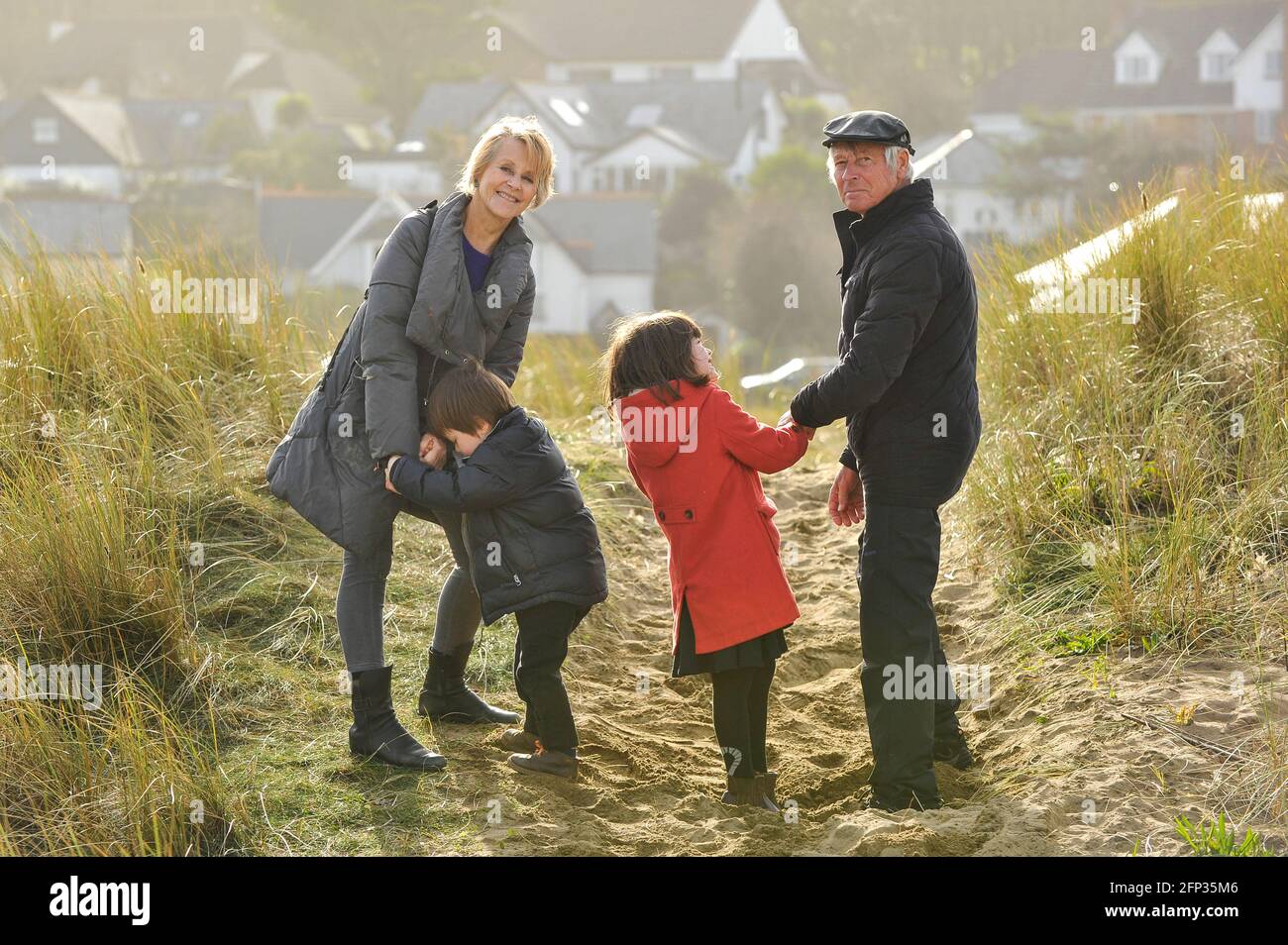A retired couple spending time with their grandchildren on a holiday in Cornwall UK. Walking through sand dunes and playing on the beach. Stock Photo