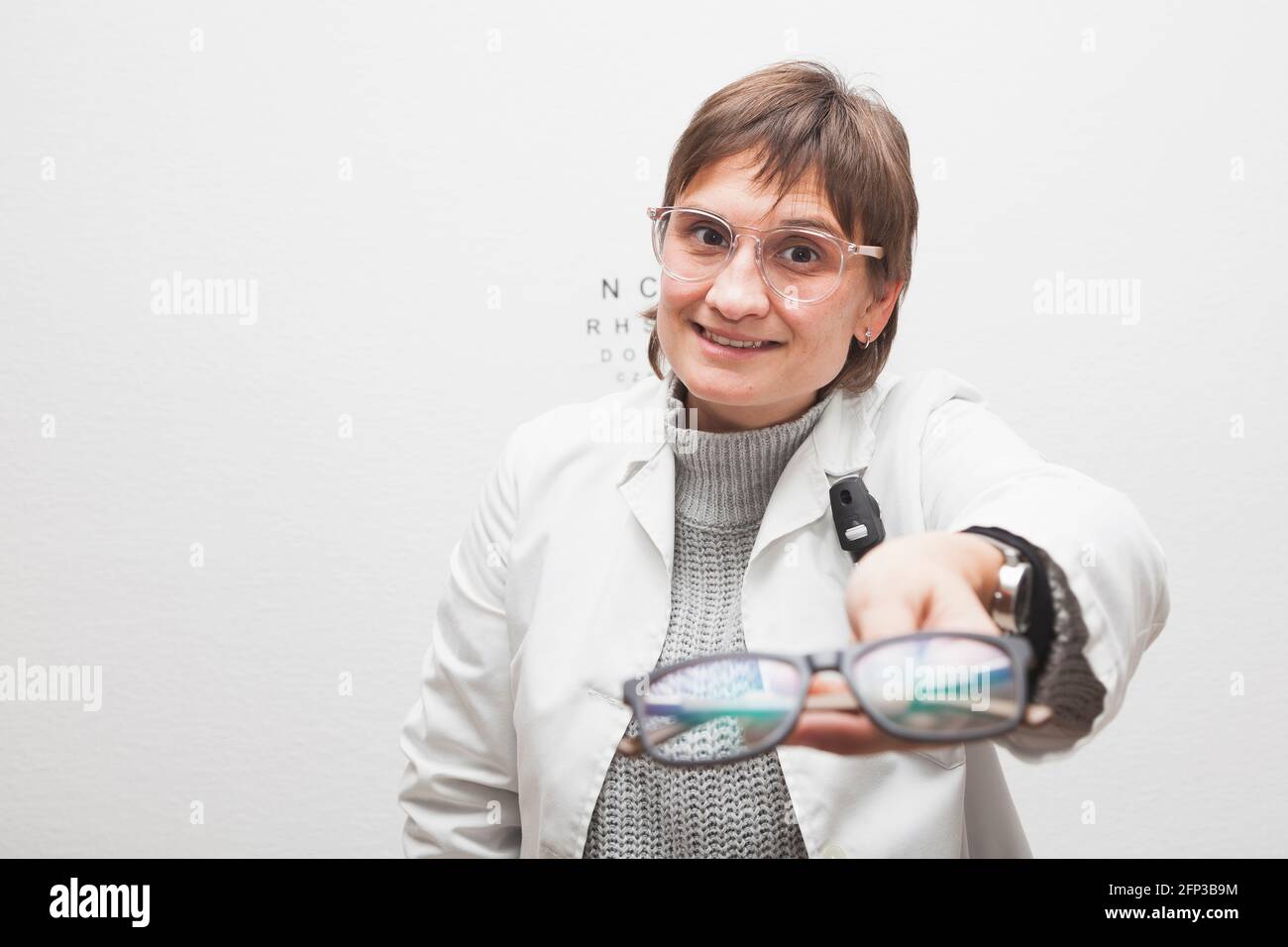 An optician's employee hands a customer new glasses, seen in the first