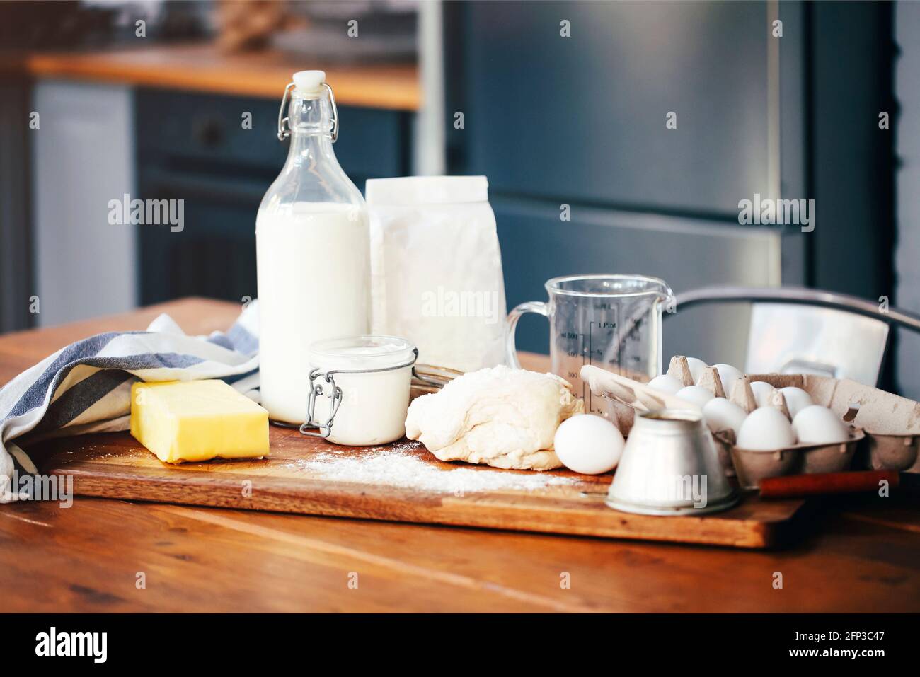 Assorted ingredients for pastry preparation placed on wooden chopping board on table in kitchen Stock Photo
