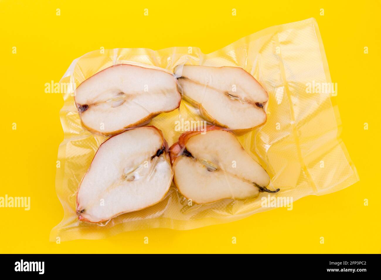 Pears cut in half in vacuum sealed for sous vide cooking, isolated on yellow background Stock Photo