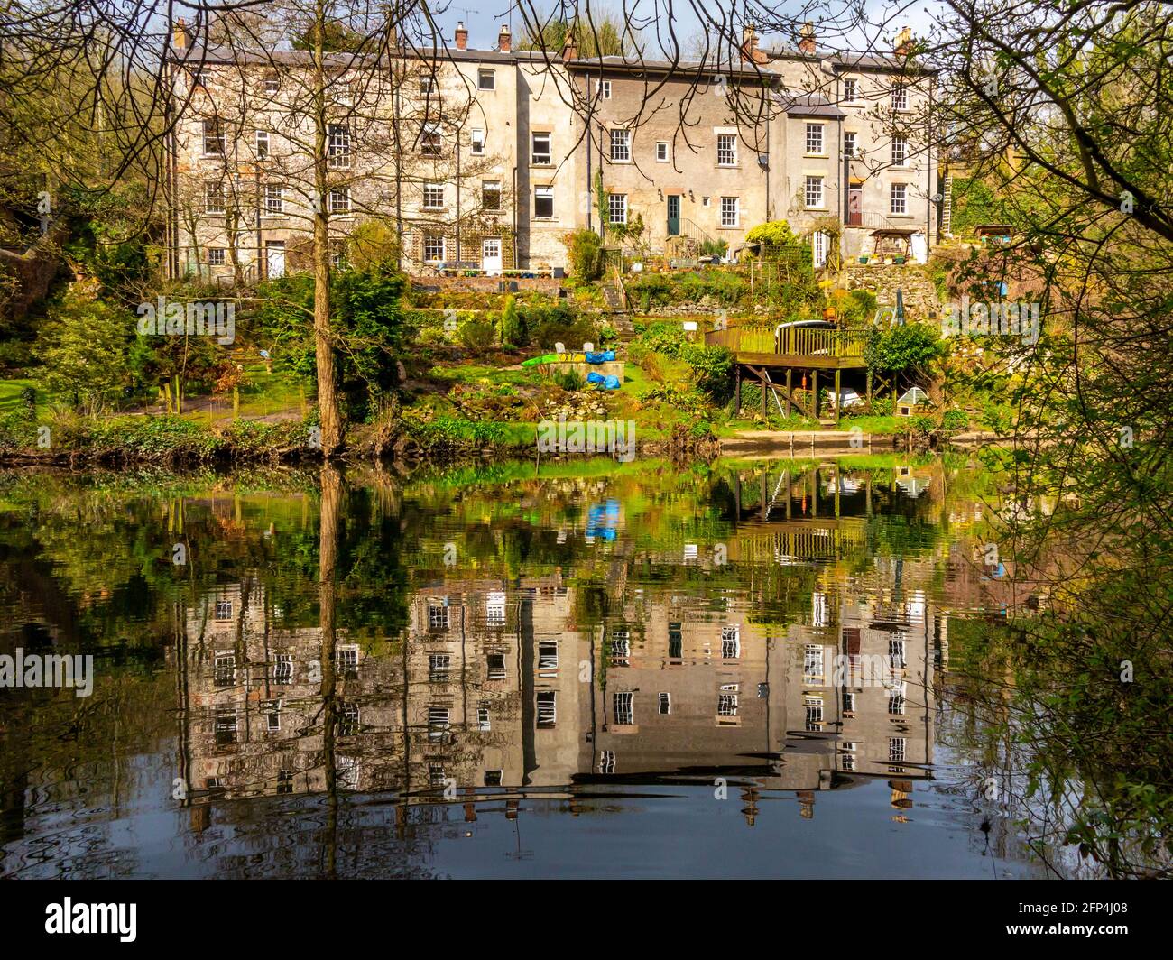 Houses reflected in the calm water of the River Derwent at Matlock Bath a village in the