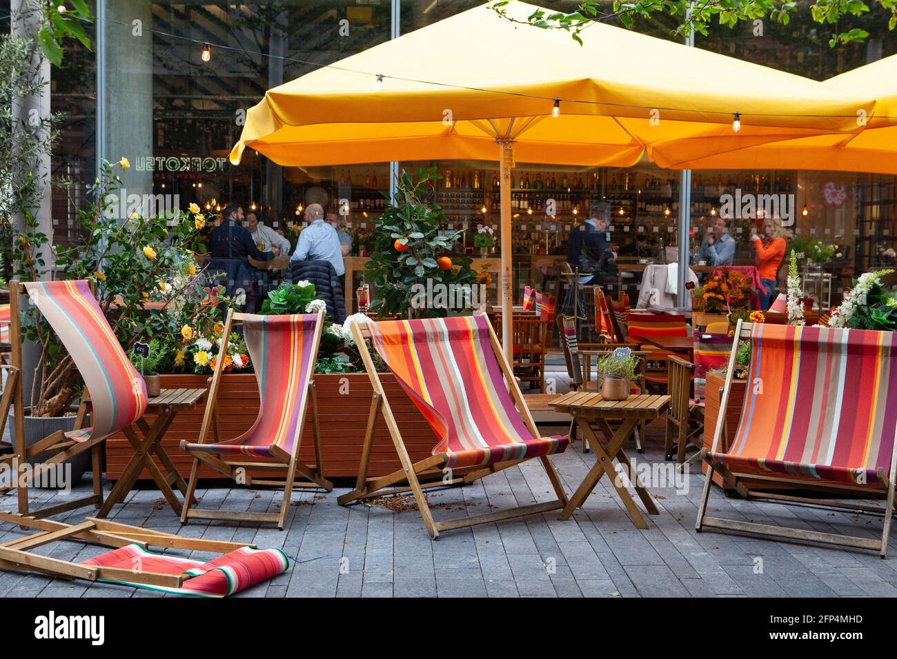 London, UK, 20 May 2021: Windy weather sends deckchairs tumblingat The Refinery restaurantnear the South Bank. But due to the recent relaxation of coronavirus regulations diners are now happily inside, provided they follow the rule of six. Anna Watson/Alamy Live News Stock Photo