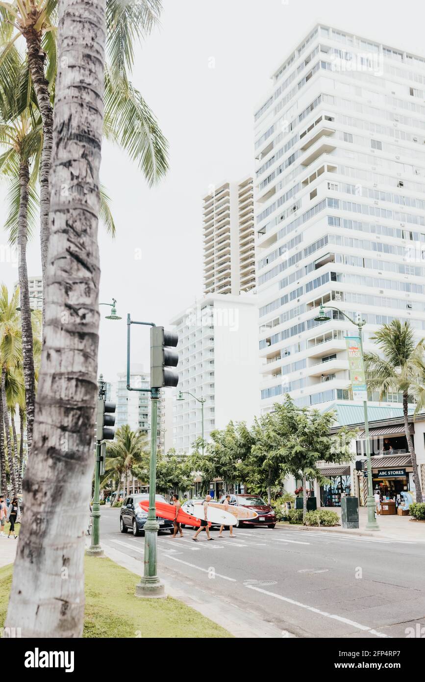 Men cross the street with surfboards in Waikiki Stock Photo
