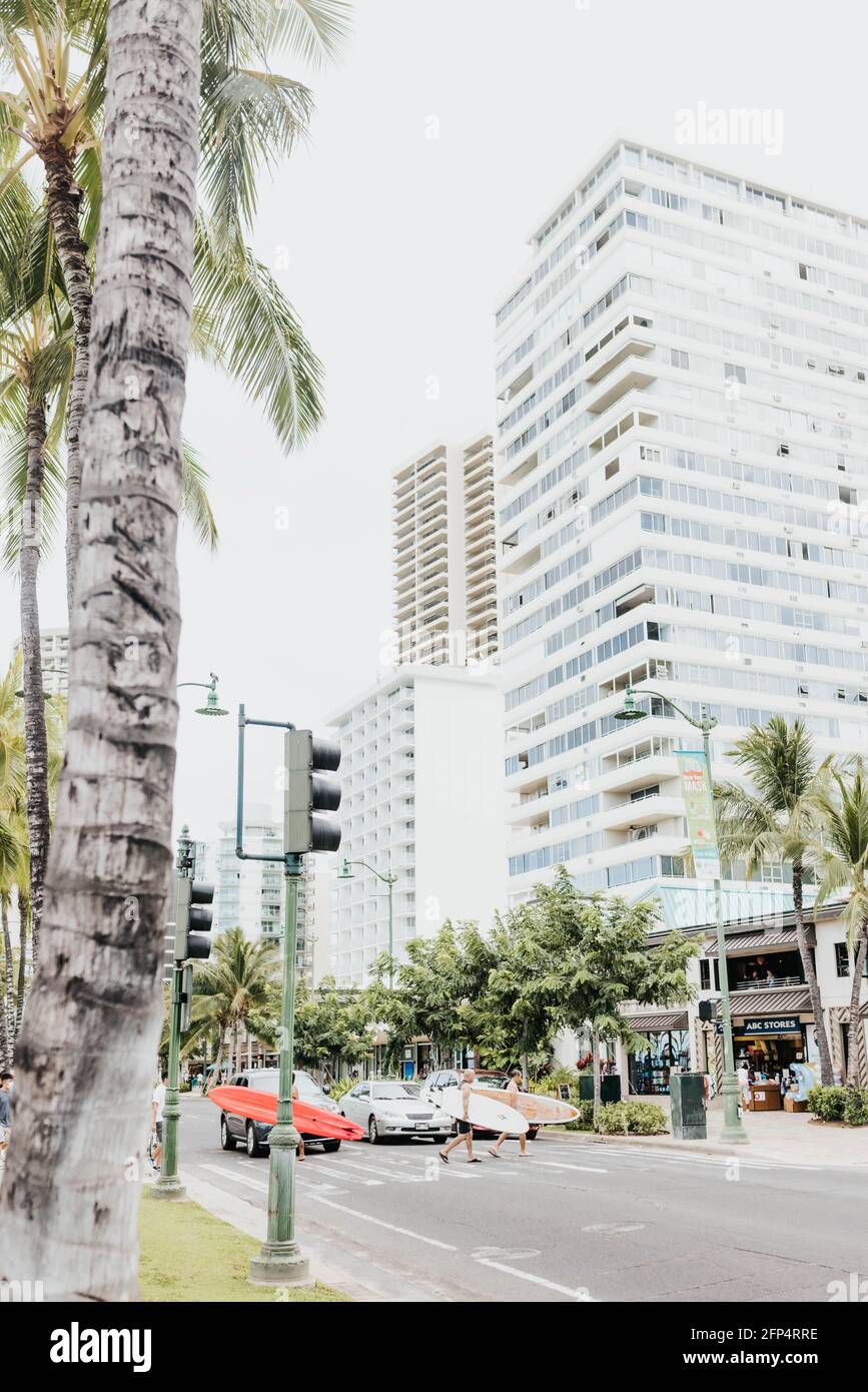 Men cross the street with surfboards in Waikiki Stock Photo