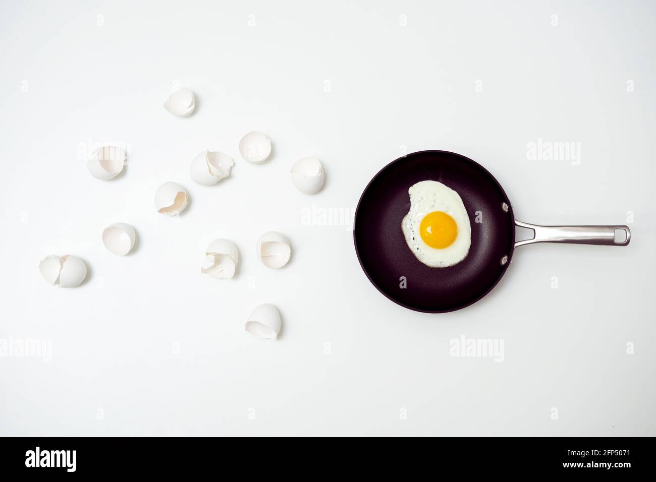 scrambled eggs with whole yolk on pan and broken shells Stock Photo