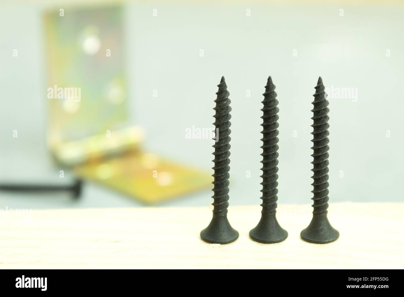 Black construction screws on a wooden background. Fasteners, canopy. Black screws and tools close-up, space for text. Background with place for text Stock Photo