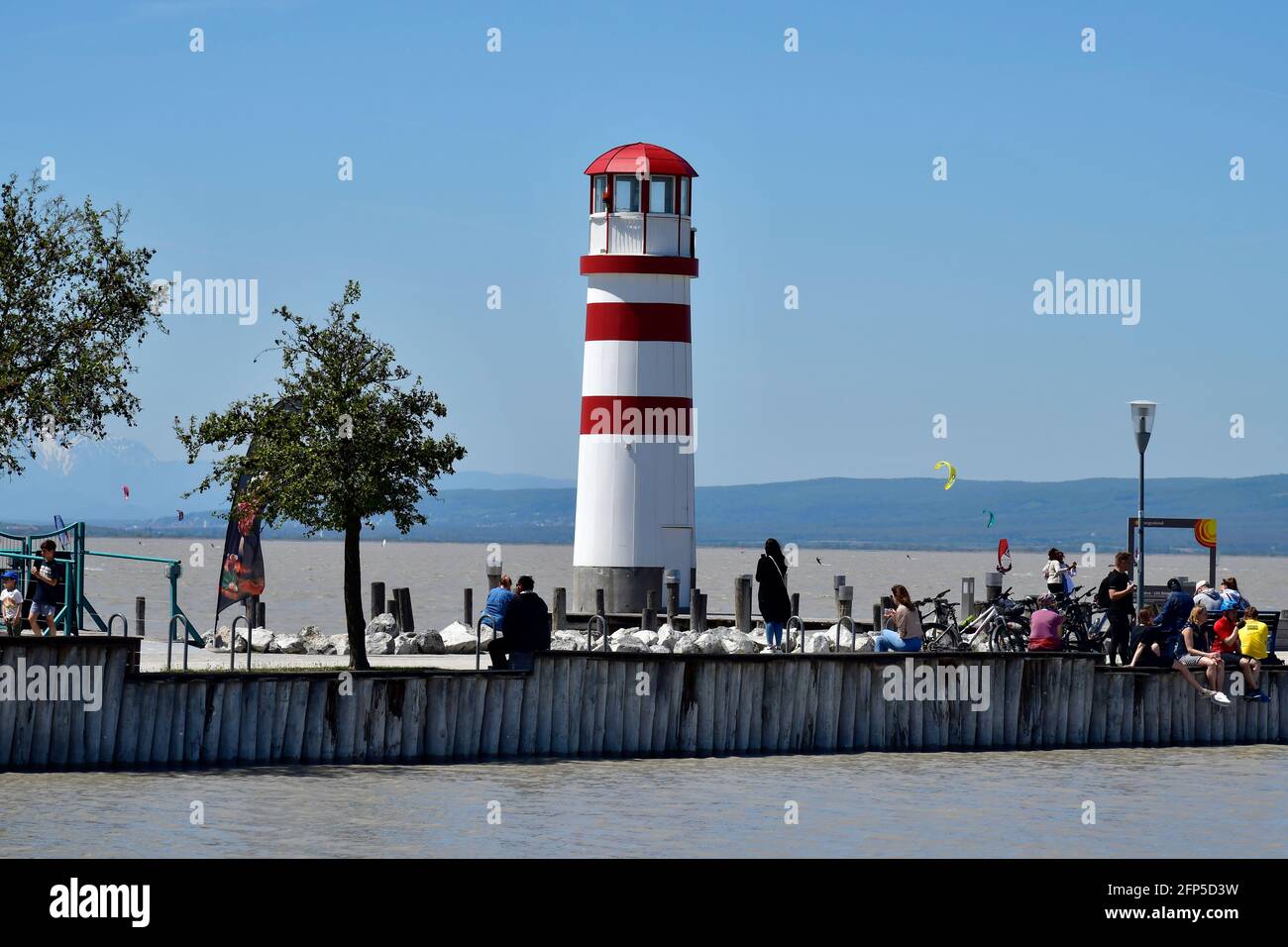 Podersdorf, Austria - May 029, 2021: Unidentified people on jetty with lighthouse in the seaside resort on lake neusiedlersee, a preferred travel dest Stock Photo
