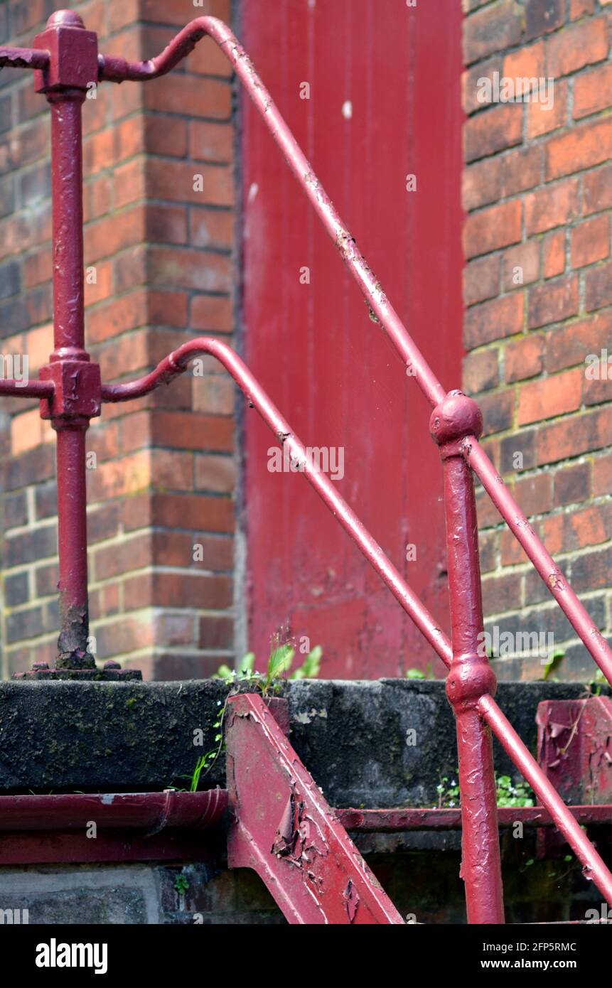 closed shut  red door and weathered red painted steps and handrail Stock Photo