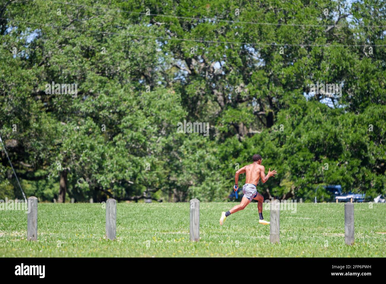 NEW ORLEANS, LA, USA - MAY 7, 2021: Young man sprints with a baton in his left hand Stock Photo