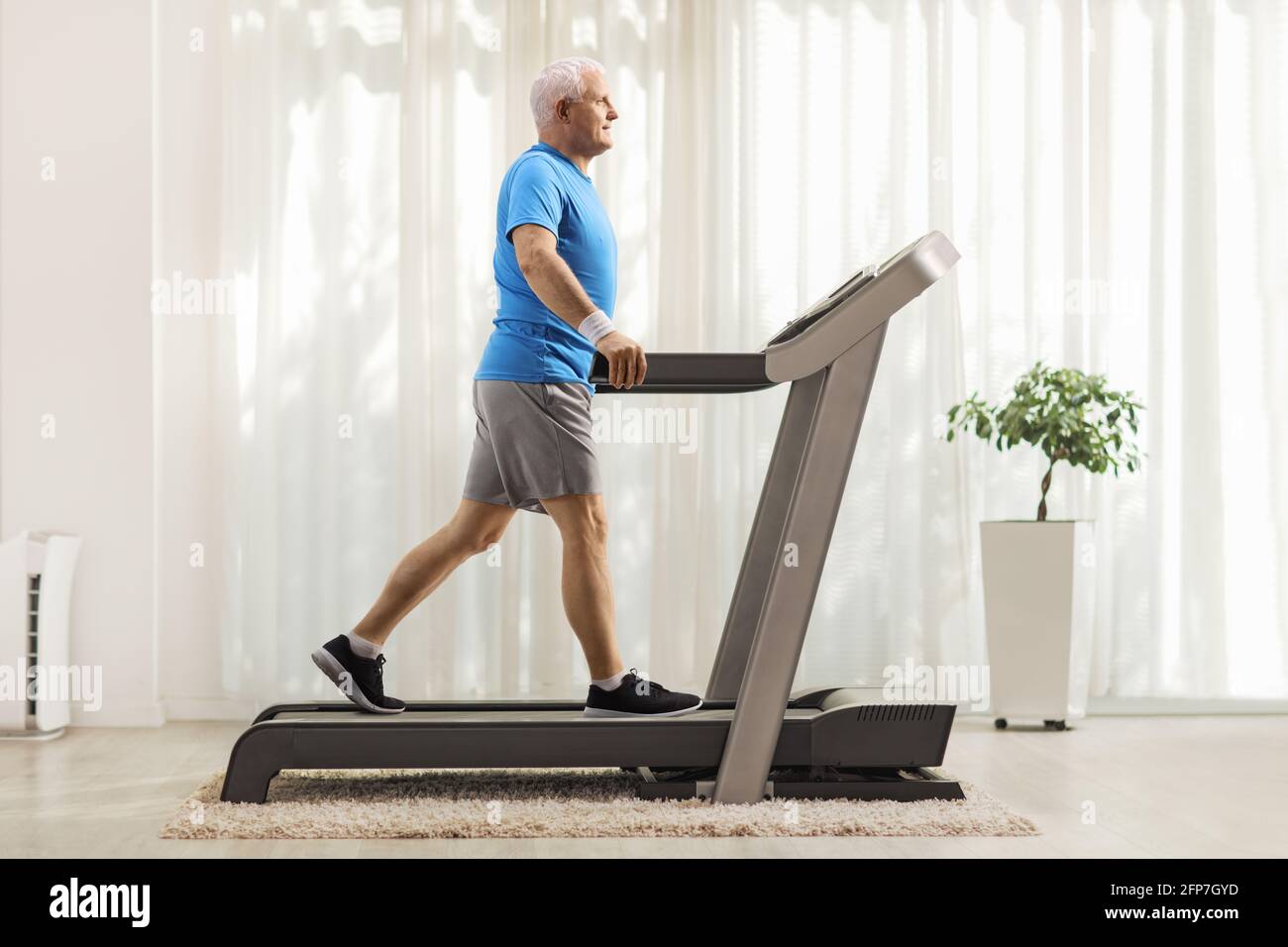 Full length profile shot of a mature man walking on a treadmill at home  Stock Photo - Alamy