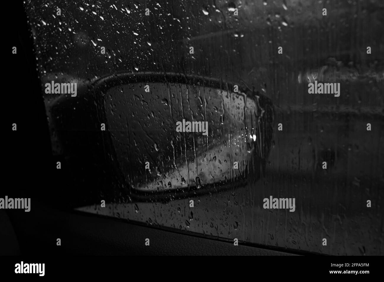 Car side mirror with headlight reflection in rain Stock Photo
