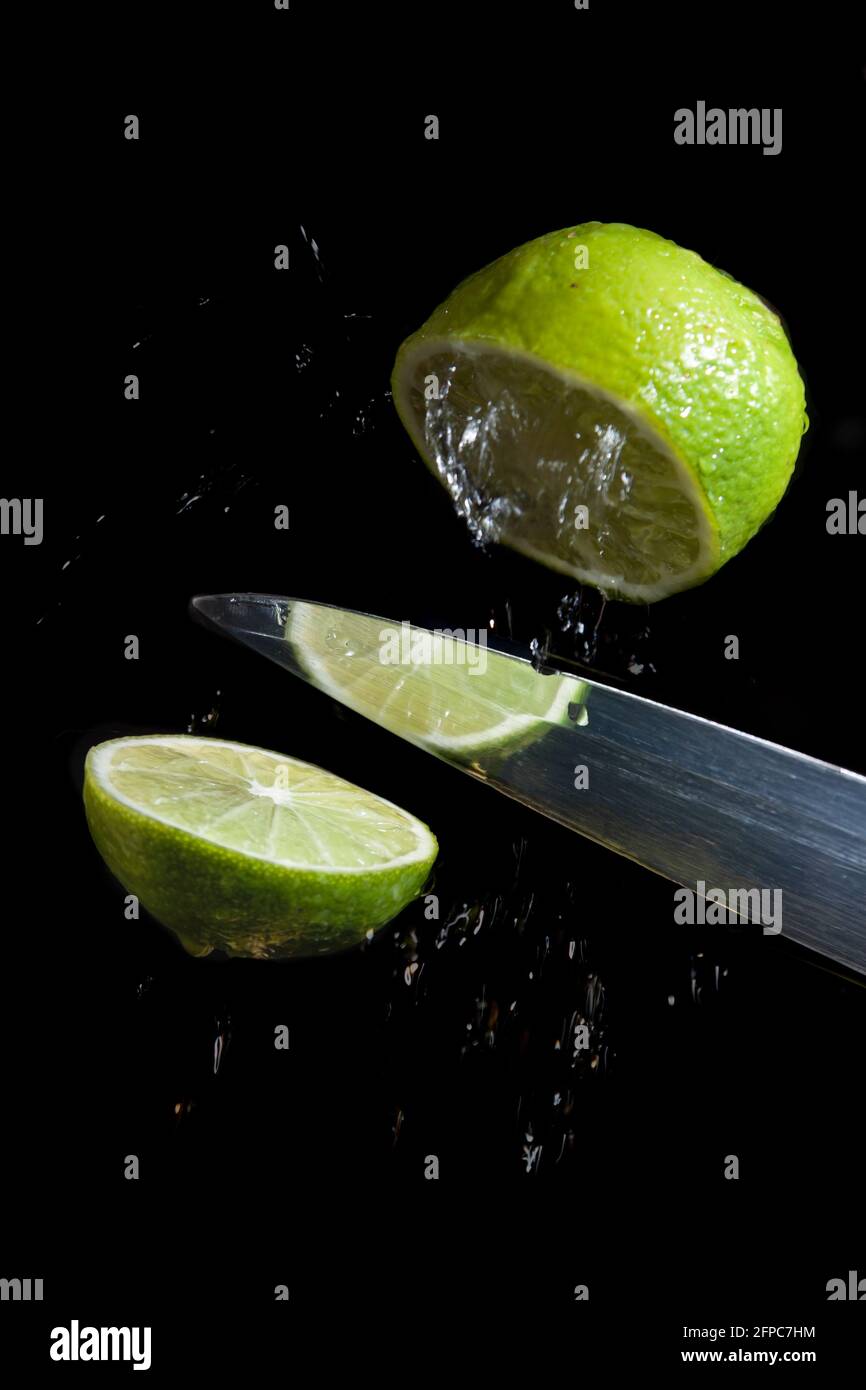 Knife cuts lime in levitation on black background Stock Photo Alamy
