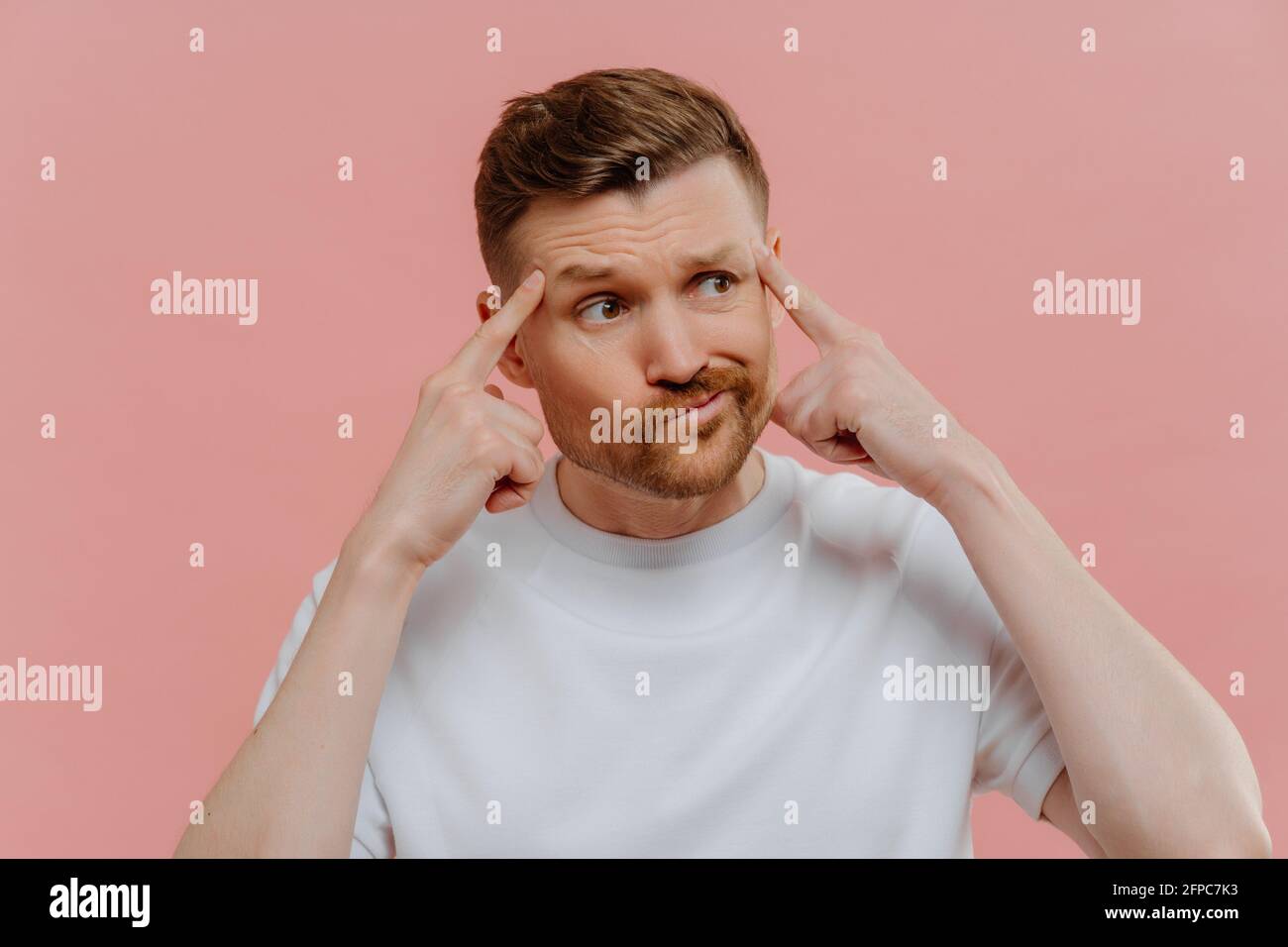 Young man thinking about something and holding fingers on his temples Stock Photo