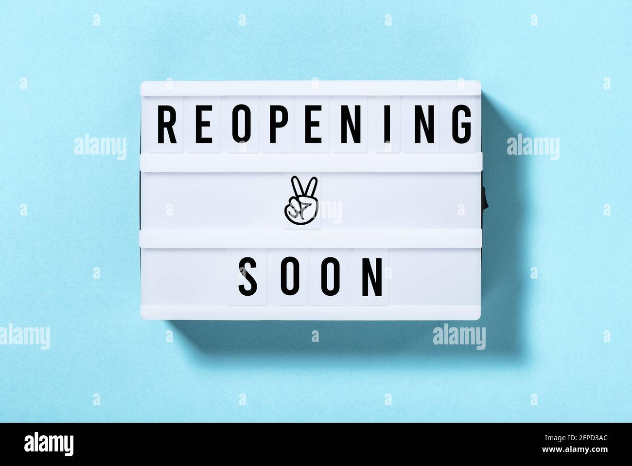 Reopening soon. Light box with text on blue background Stock Photo