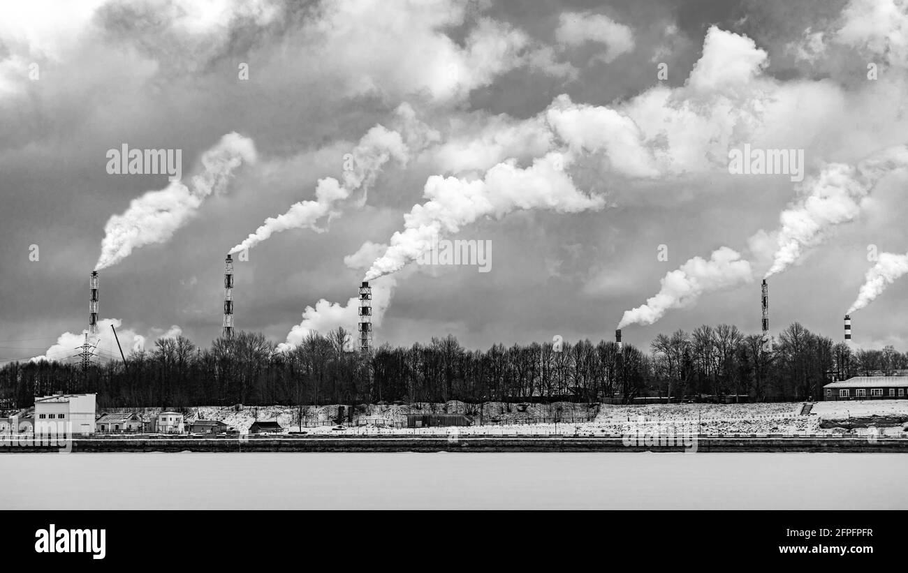 Funnels give off a heavy factory smoke. Harmful chemical waste. Air pollution. Monochrome photo Stock Photo