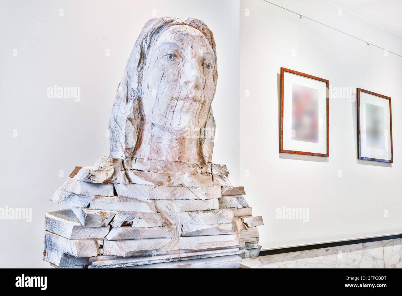 Detail of modern home interior design with stone bust sculpture and framed pictures in room with white walls Stock Photo