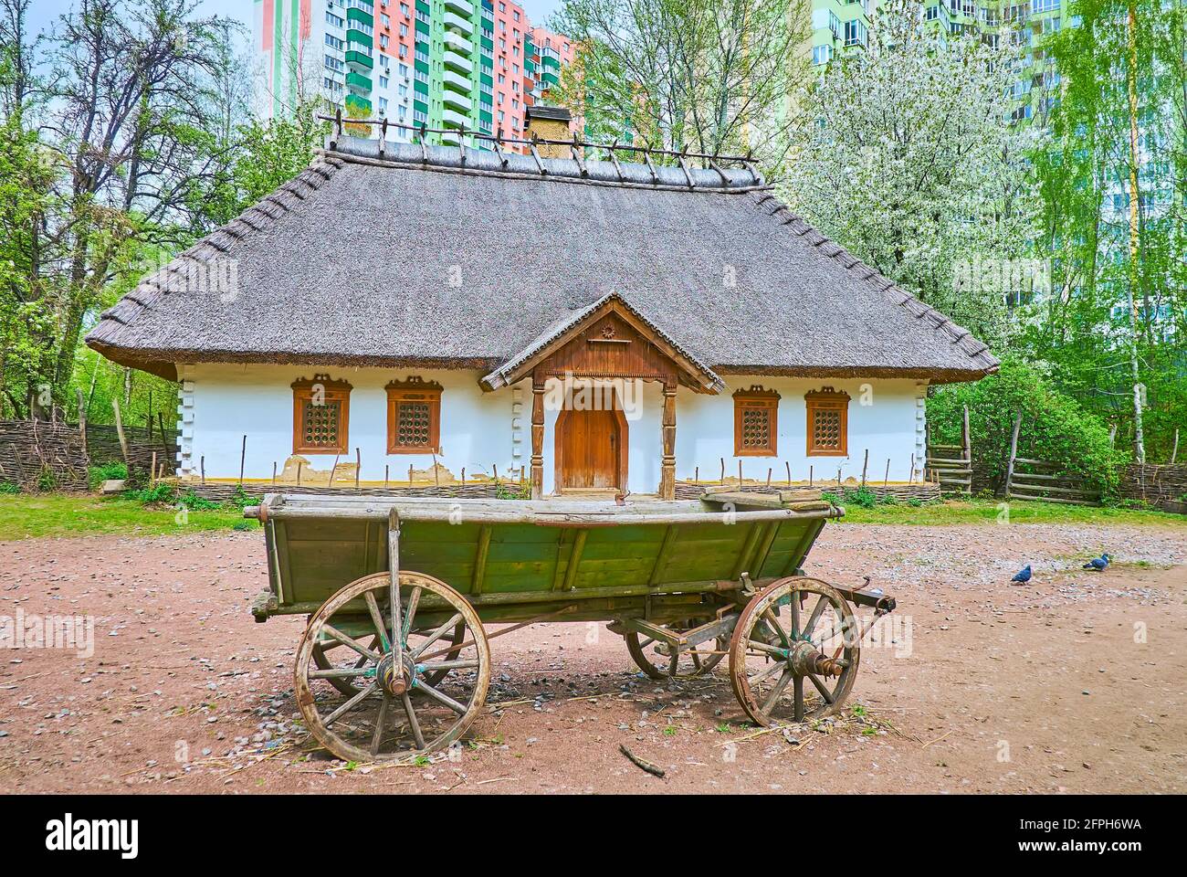 The grounds of historic Churchwarden's estate with whitewashed house and the old wooden cart, located in Mamajeva Sloboda Cossack Village scansen, Kyi Stock Photo