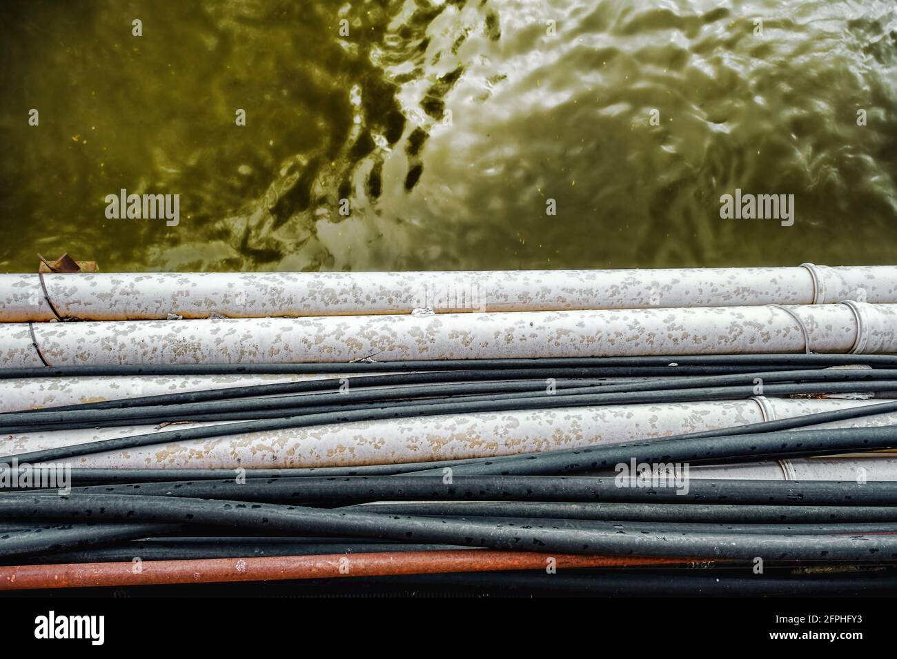 electrical cables and pipes over dirty water Stock Photo Alamy