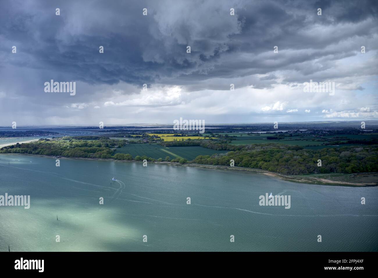 Dark cumulus storm clouds over the West Sussex countryside and estuary near Chichester Marina with sailing boats in the water. Aerial photo. Stock Photo