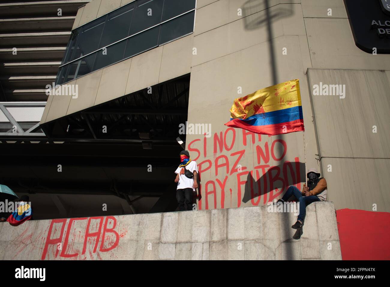 Bogota, Cundinamarca, Colombia. 19th May, 2021. Protester waves the Colombian flag while next to him there is a mural that says ''if there is no peace, there is no football'' against the realization of the American Cup in the country, while protests increase in BogotÃ¡ on May 20, 2021 in the context of a national strike in Colombia against the tax reform and the government of IvÃ¡n Duque. Credit: Daniel Romero/LongVisual/ZUMA Wire/Alamy Live News Stock Photo