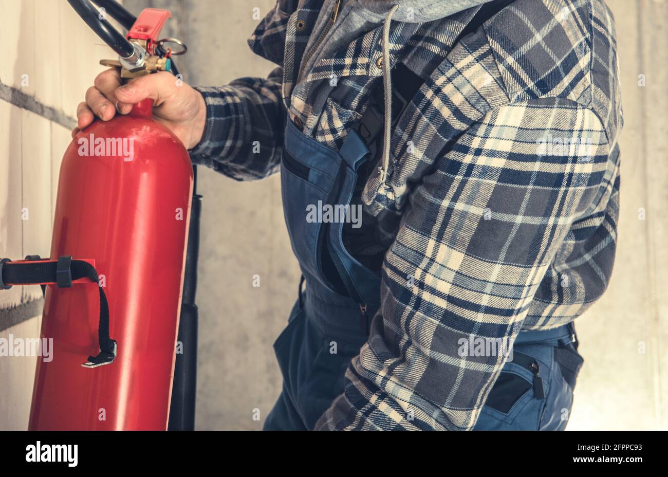 Red Extinguisher Installation Inside Commercial Building by Professional Fire Safety Worker