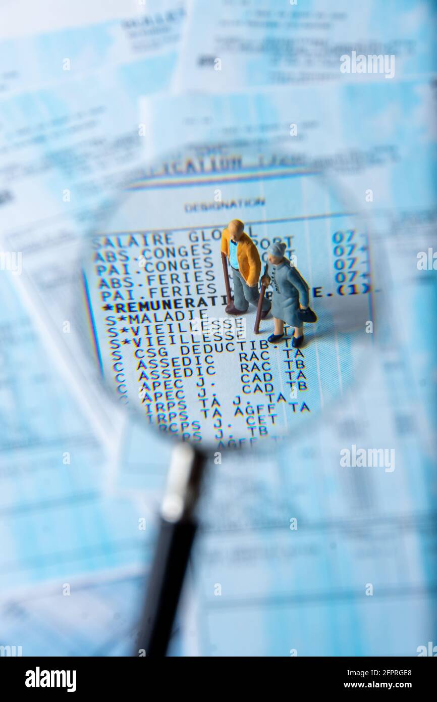 French payroll seen in detail through a magnifying glass showing social security contributions for retirement and sickness, with small figurines Stock Photo