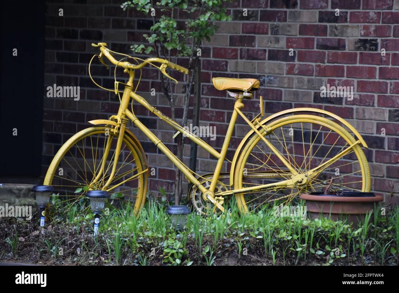 Yellow girls bike in an East Texas flower bed Stock Photo