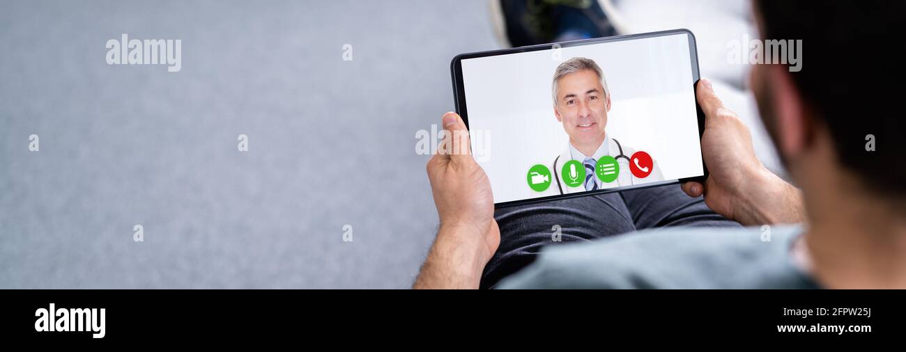 Man Having Video Chat With Doctor On Laptop At Home Stock Photo