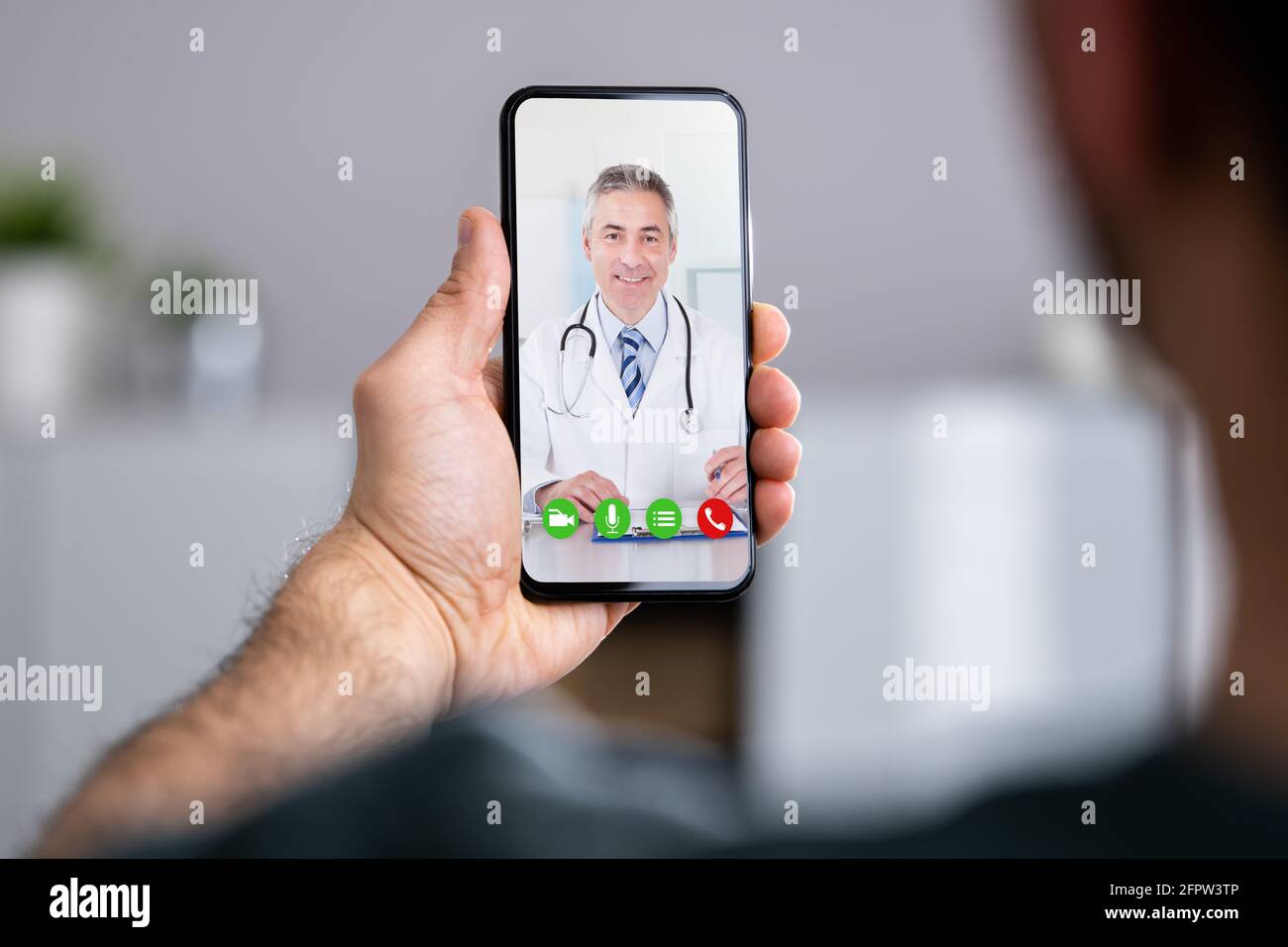 Man Having Video Chat With Doctor On Phone At Home Stock Photo