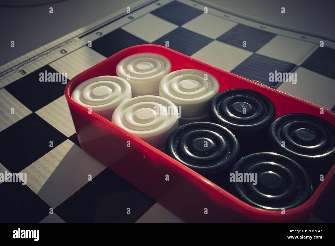 Board game of checkers. Black and white chips for the game. Chess field. Checkers move close-up. Checker in hand. Stock Photo