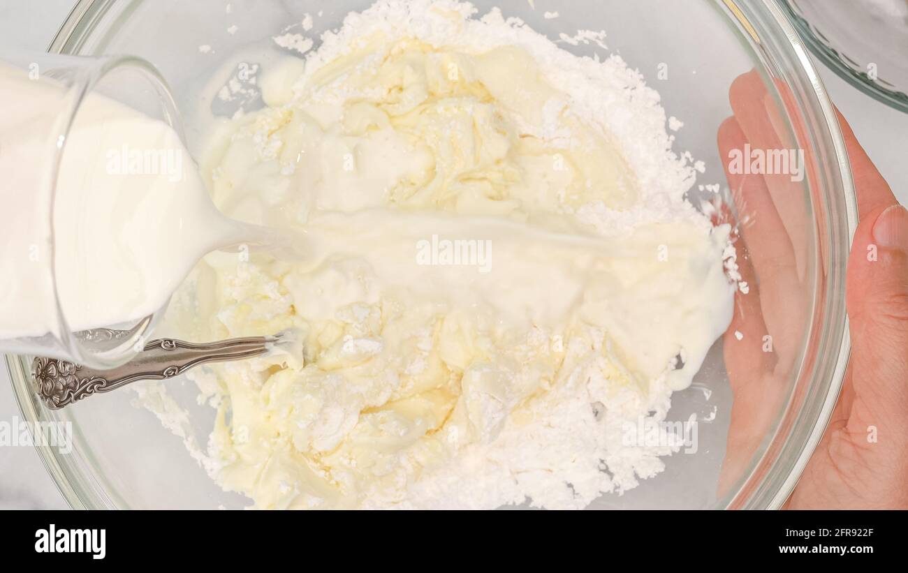 Cream cheese, powdered sugar and milk cream mixing in a glass bowl