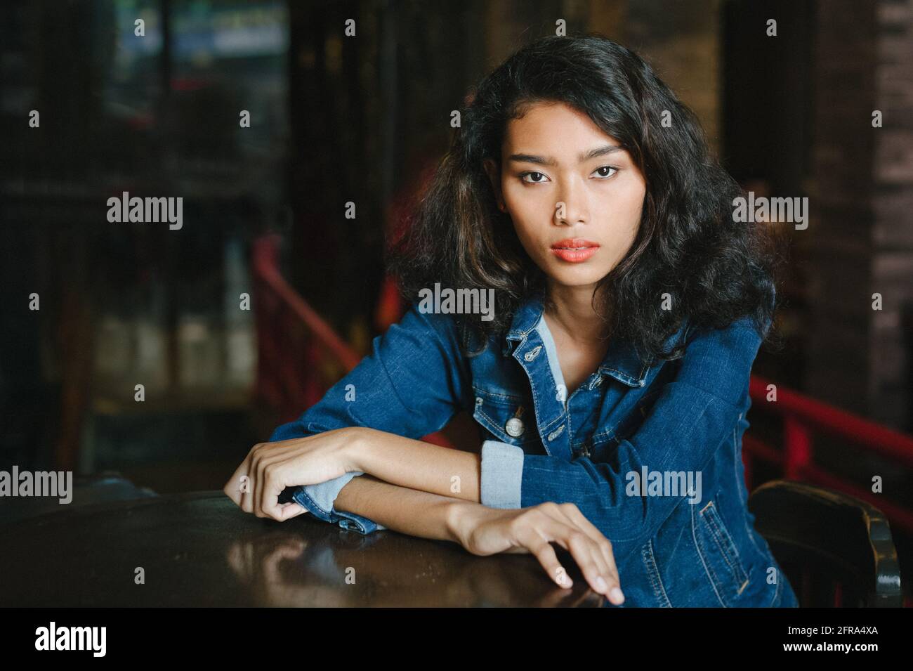 Portrait of a young beautiful Asian woman wearing blue jeans jacket ...