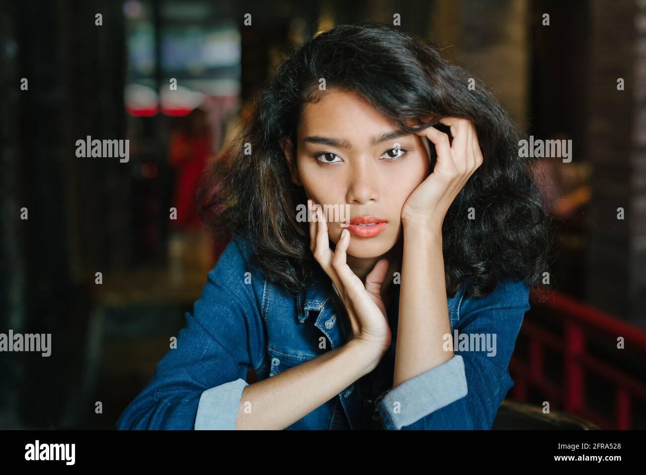 Portrait of a young beautiful Asian woman wearing blue jeans jacket ...