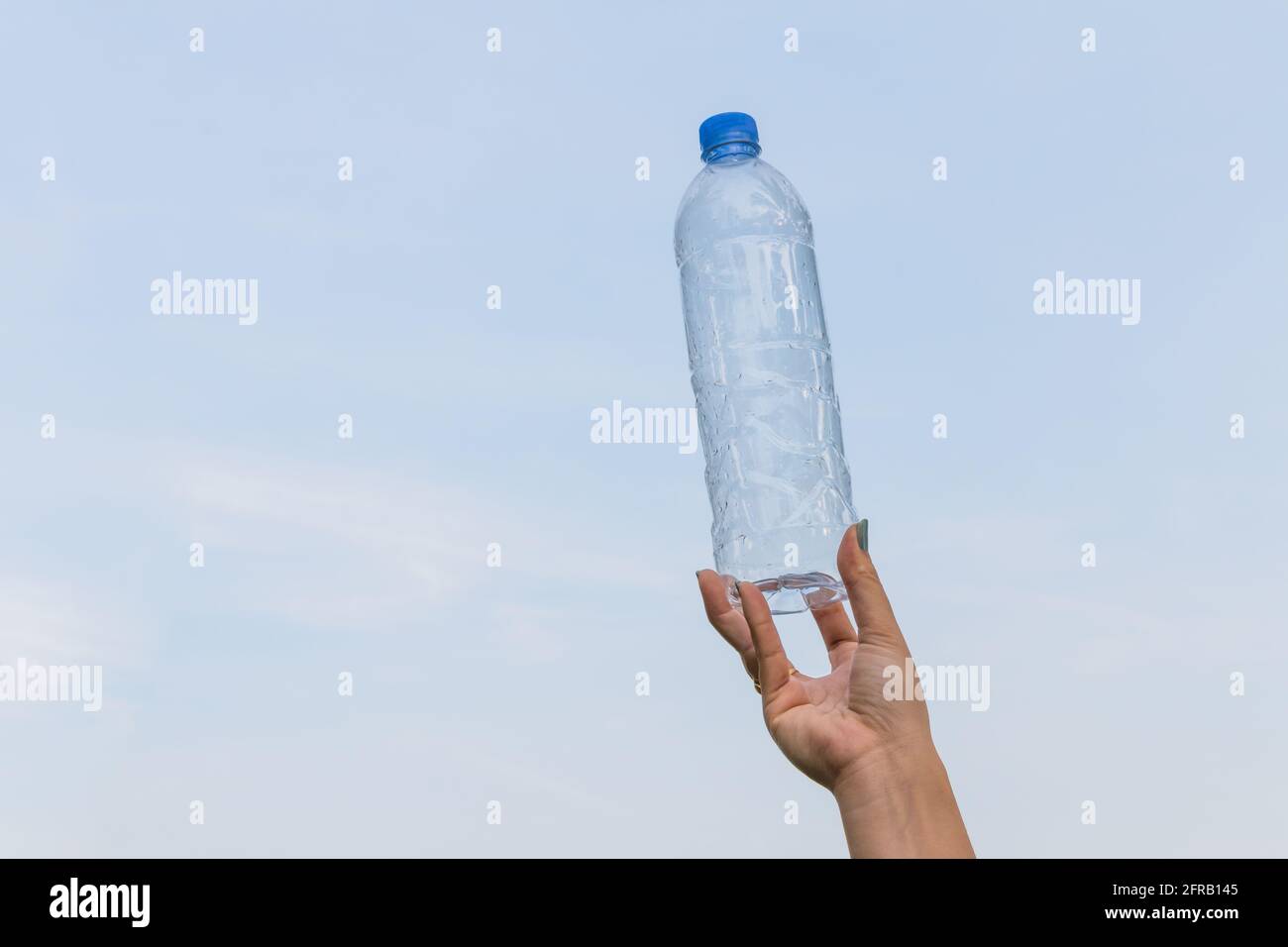 Woman hand hold bottle of drinking water on a blue sky background Stock ...