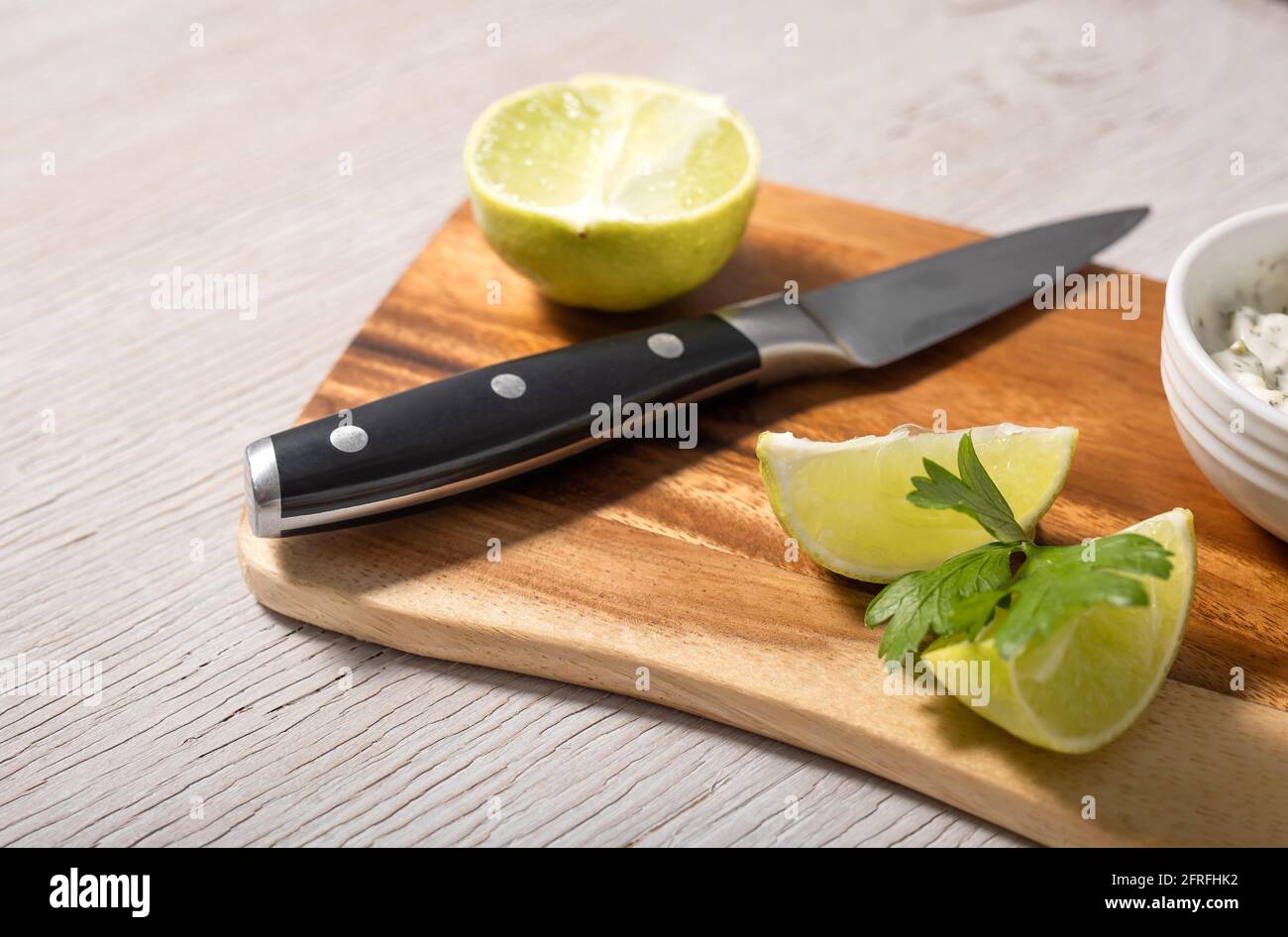 Sliced lime and black knife on wooden cutting board Stock Photo
