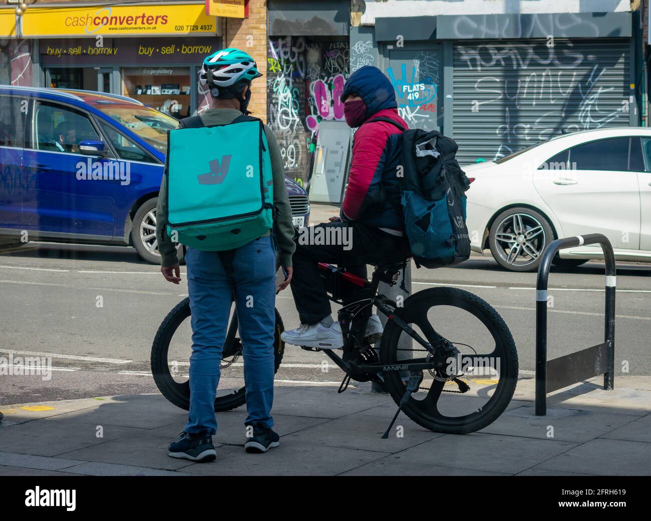 London. UK- 05.18.2021: two young man working as self employed home delivery riders working for online food ordering companies having a chat. Stock Photo